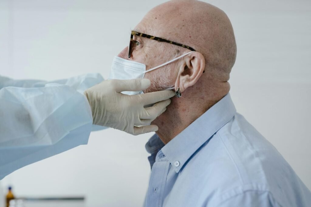 Side view of bald man with glasses wearing a face mask during a medical checkup.